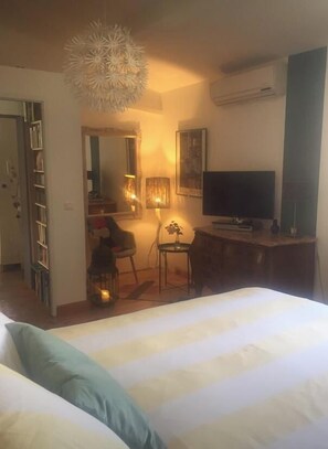 Quarto de hotel com cama, escrivaninha, televisão e cadeira.