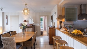 Une cuisine chaleureuse avec une table à manger en bois, des chaises en osier et un luminaire suspendu.