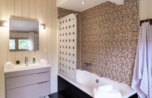 A bathroom with a white vanity, a large mirror, a shower with a mosaic wall, and a striped towel hanging on the wall. - stylish villa with beautiful sea view and heated pool (May to Sept) (Lège-Cap-Ferret)