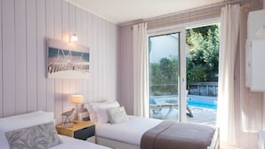 Une chambre d’hôtel avec deux lits, un tableau, une lampe et une vue sur une piscine.