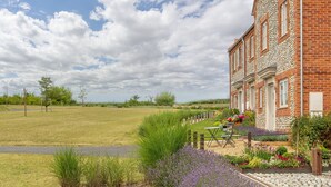 A brick building with a garden and outdoor seating area.