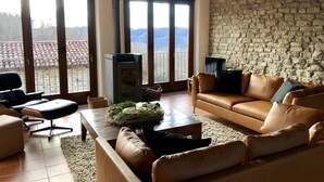 A living room with a stone wall, leather sofa, and a fireplace.