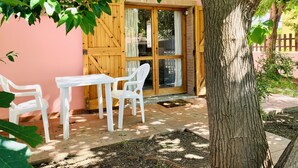 Eine Terrasse mit Tisch und Stühlen, eine Holztür und ein Baum.