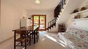 Ein gemütlicher Wohnraum mit Essbereich, einer Couch, einer Treppe und einer Küchenzeile.