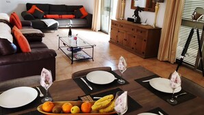 A dining area with a table set for four, a sofa, a cabinet, and a glass coffee table. - Luxury 3Bed Villa, Large Heated Pool, Wifi, Sun Terrace, Sea & Golf Course Views (Caleta De Fuste)