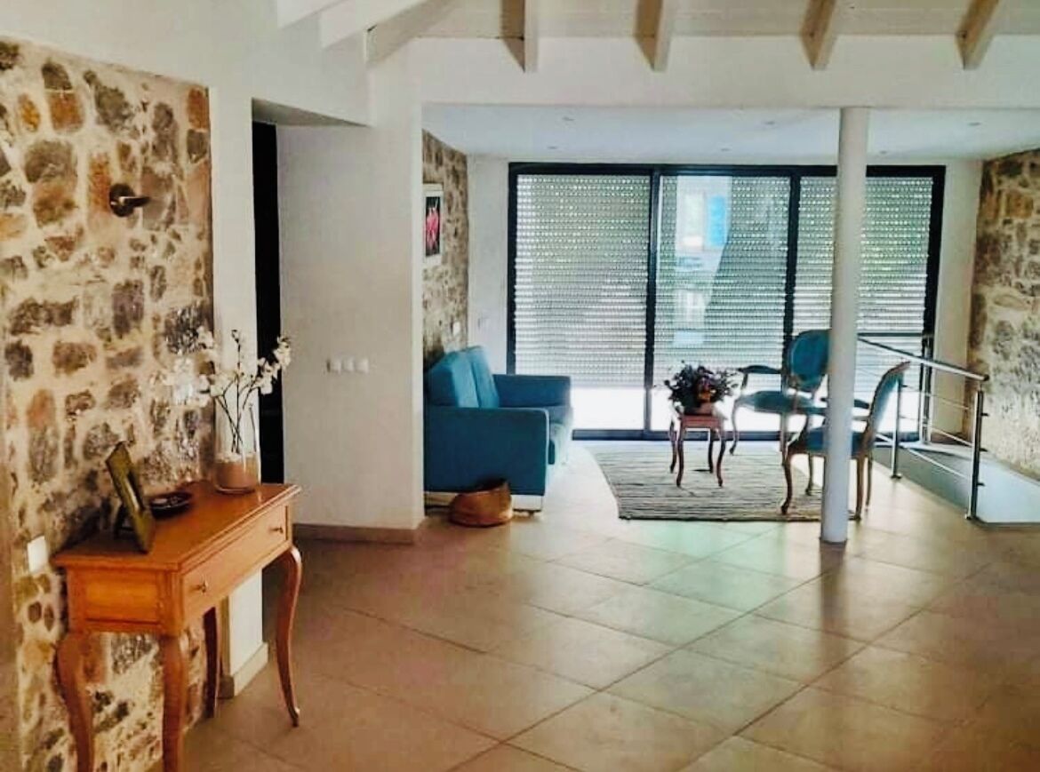 Un amplio espacio de estar con un sofá azul, una mesita de madera y una escalera que lleva a un piso superior.