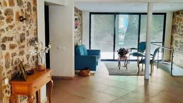 Un amplio espacio de estar con un sofá azul, una mesita de madera y una escalera que lleva a un piso superior.