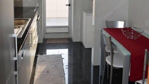 A modern kitchen with a dining area, a view through the door, and a red tablecloth on the dining table. - “Musical View” – Fabulous view of the “Casa da Música” and surrounding area (Porto)