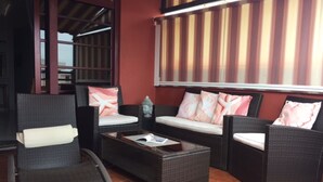 A seating area with wicker furniture and a cushioned bench, a small table, and a decorative Buddha statue.