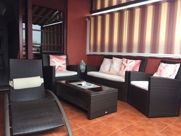 A seating area with wicker furniture and a cushioned bench, a small table, and a decorative Buddha statue. - Cozy and bright penthouse (Puertito de Güímar)
