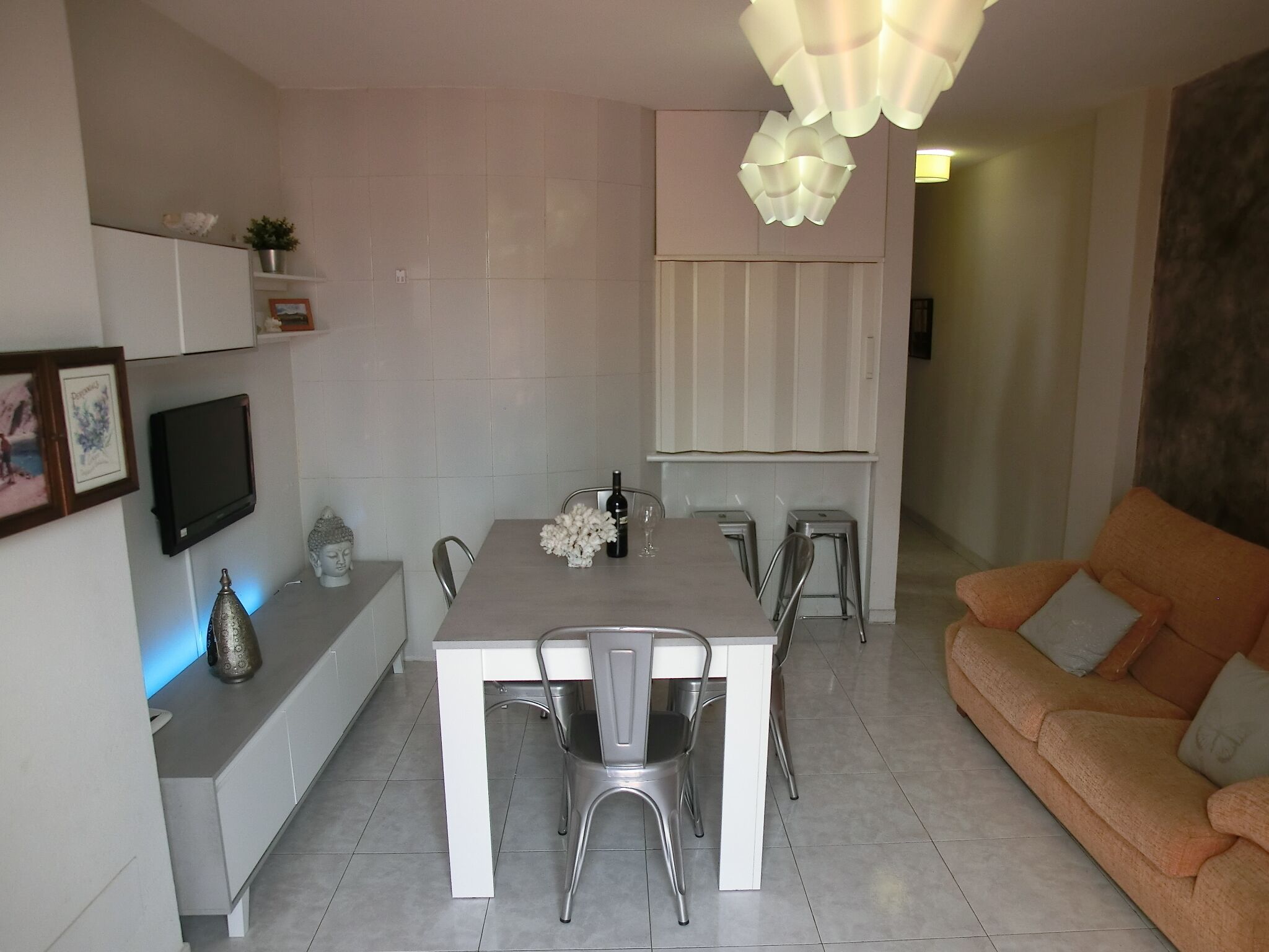A modern kitchen with a dining table, chairs, and a sofa.