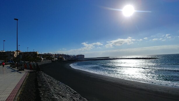 A coastal promenade with a paved walkway, a stone wall, and a view of the sea.