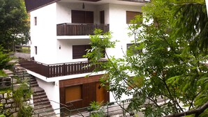 A multi-story building with balconies, a staircase, and surrounding greenery. - Adjacent to the pedestrian zone - 025016-LOC-01432 (Cortina d'Ampezzo)