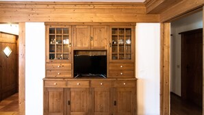 A wooden entertainment center with a flat-screen TV, drawers, and glass-front cabinets. - Adjacent to the pedestrian zone - 025016-LOC-01432 (Cortina d'Ampezzo)
