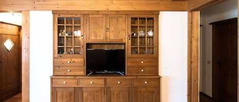 Un meuble de rangement en bois, doté d’un téléviseur à écran plat, de tiroirs et d’armoires à portes vitrées.