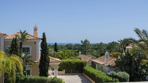 Eine Villa im mediterranen Stil mit einem Ziegeldach, einem Glockenturm und üppiger Vegetation.