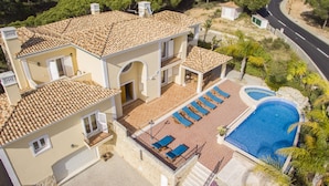 Ein zweistöckiges Haus mit Swimmingpool, Balkon und gepflasterter Terrasse.