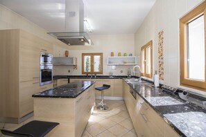 A modern kitchen with a central island, built-in oven, and stainless steel appliances.