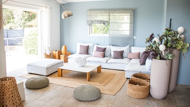 Ein modernes Wohnzimmer mit einem weißen Sofa, einem Couchtisch und einem großen Fenster mit Vorhängen.