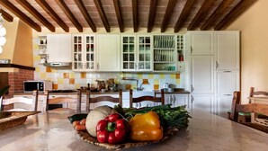 Cozinha com armários brancos, painel de azulejos e teto de madeira.