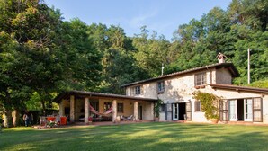 Uma casa de dois andares com um espaço de varanda, uma rede e um espaço para refeições.