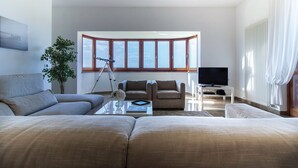 A modern living room with a large sofa, a coffee table, and a television. There is a telescope and a potted plant in the room. - Exclusive Villa with Spectacular Panoramic Views - Excellent location ★★★★★ (Pescara)