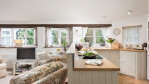 Una cocina moderna con una isla central, armarios blancos y un comedor con un sofá floral.