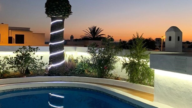 A swimming pool with a palm tree and a sunset view. - Villa in Puerto del Carmen, Lanzarote, Canary Islands  (Tías)