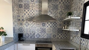 A kitchen with patterned tiles, a built-in oven, a coffee maker, and a sink with a towel. - Villa in Puerto del Carmen, Lanzarote, Canary Islands  (Tías)