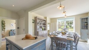 Una cocina amplia con una isla central, armarios de madera y un comedor con sillas.