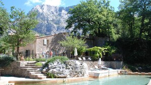 A pool area with a stone building, steps leading to a terrace, and a mountainous backdrop. - LA FEUILLERE, 17 CENTURY MANSION.  (Saint Antonin sur Bayon)