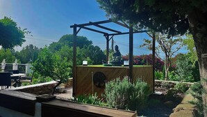 A wooden pergola with a Buddha statue, surrounded by lush greenery and a small pond.