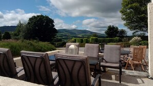 An outdoor seating area with a view of rolling hills and a partly cloudy sky. - Family Friendly Spacious Home On Large Grounds With Panoramic Views (Aughrim)