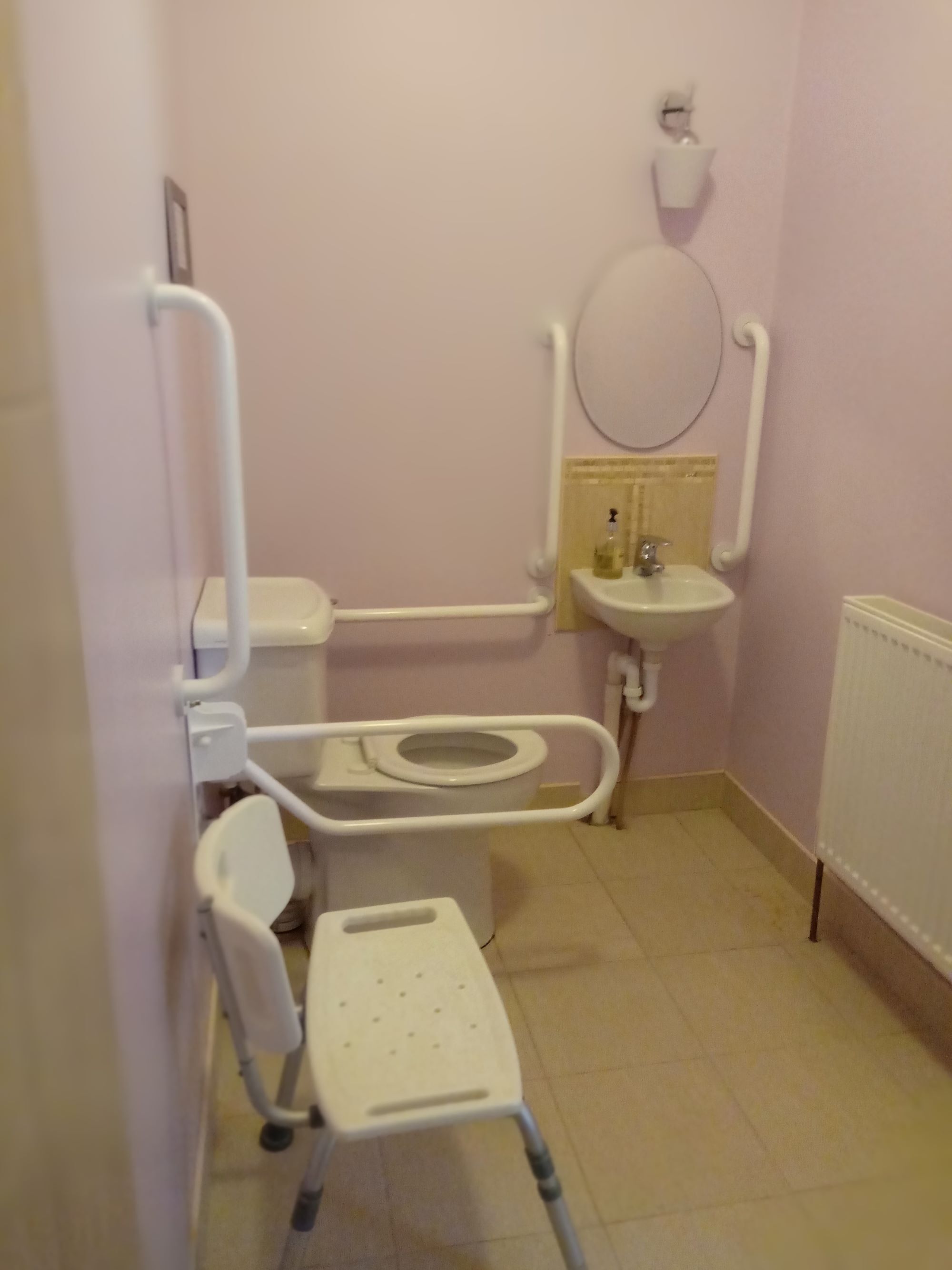A small, private bathroom with a toilet, bidet, and a handrail.