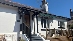 A two-story house with a white exterior, a wooden front porch, and a green awning. - St Matthias Lodge - Delightful 2 bed cottage  (Torquay)