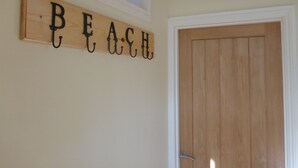 A wooden sign with the word "BEACH" spelled out in black letters, mounted on a wall above a wooden door. - St Matthias Lodge - Delightful 2 bed cottage  (Torquay)