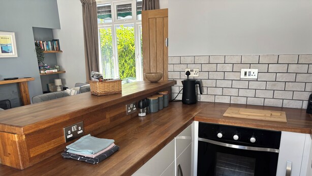 A modern kitchen with a wooden countertop, built-in oven, and a brick backsplash. - St Matthias Lodge - Delightful 2 bed cottage  (Torquay)