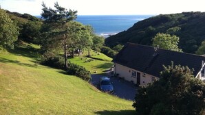 A house with a sloped roof, a driveway, and a car parked in front. - Ideal location for families who like sandy beaches and dramatic coastal scenery (Gower)