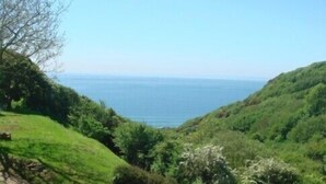 A grassy hillside with a clear view of the ocean. - Ideal location for families who like sandy beaches and dramatic coastal scenery (Gower)