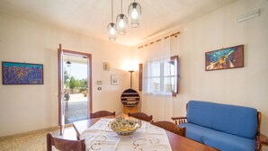 A dining area with a wooden table, chairs, a blue sofa, and a decorative bowl.