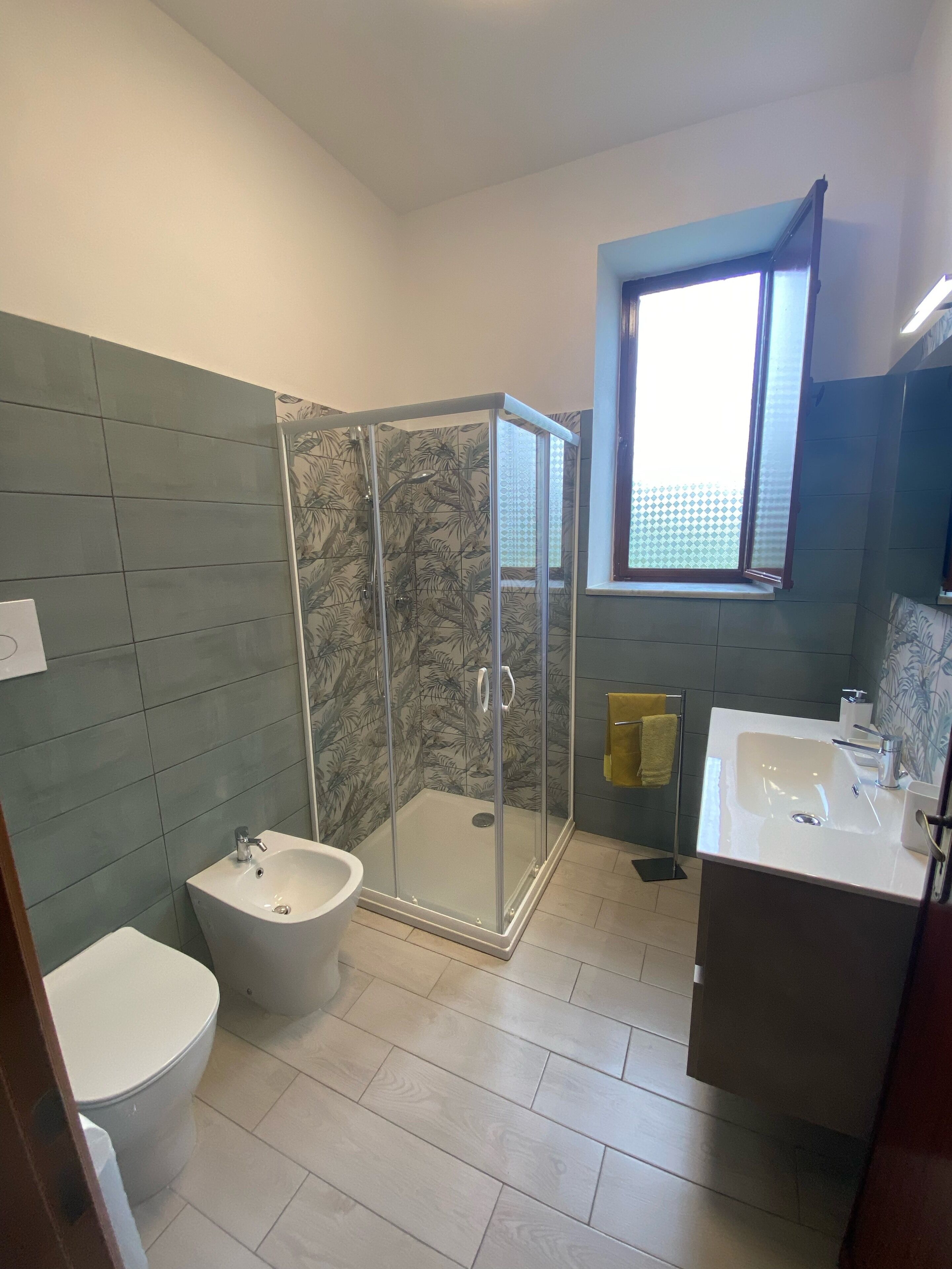 A bathroom with a glass-enclosed shower, a white sink, and a toilet.