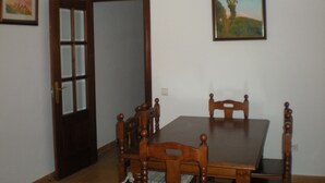 Une salle à manger avec une table et des chaises en bois, un lustre et un tableau au mur.