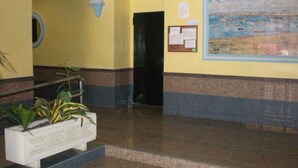 Un hall d’entrée avec un escalier en marbre, un tableau d’affichage et une fresque murale.