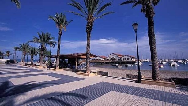 A coastal promenade with palm trees, a covered seating area, and a view of boats in the water. - Lovely 2 bedroom,2 bathroom ground floor apartment adjacent to pool Sleeps 4/5. (San Javier)