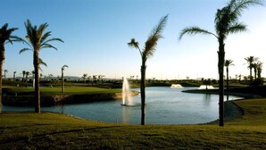 A golf course with palm trees, a pond, and a fountain. - Lovely 2 bedroom,2 bathroom ground floor apartment adjacent to pool Sleeps 4/5. (San Javier)