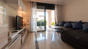 A modern living room with a flat-screen TV, a sofa, and a dining table. - Lovely 2 bedroom,2 bathroom ground floor apartment adjacent to pool Sleeps 4/5. (San Javier)