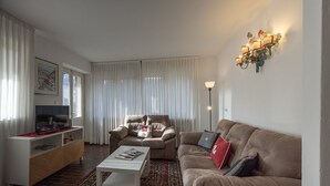 Una sala de estar con sofá, sillón, mesa de centro, televisor y un adorno de pared.