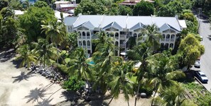 A large, multi-story building with a symmetrical facade, surrounded by palm trees and a paved area. - Spacious, Family Friendly, Top Floor, 3 Bedroom Apartment on the Beach (Stonehaven)