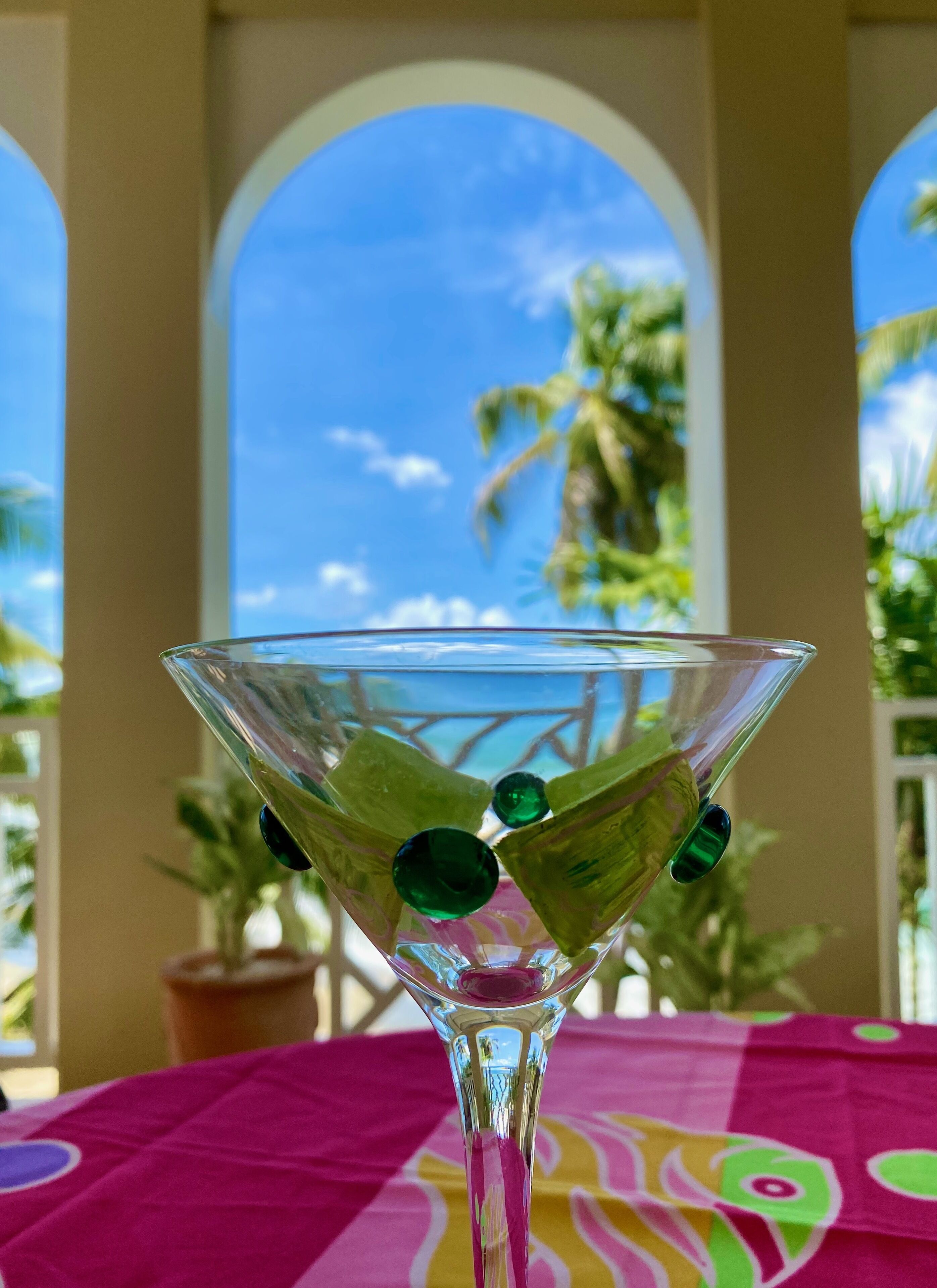 Una copa de martini con piedras verdes sobre una mesa con mantel colorido.