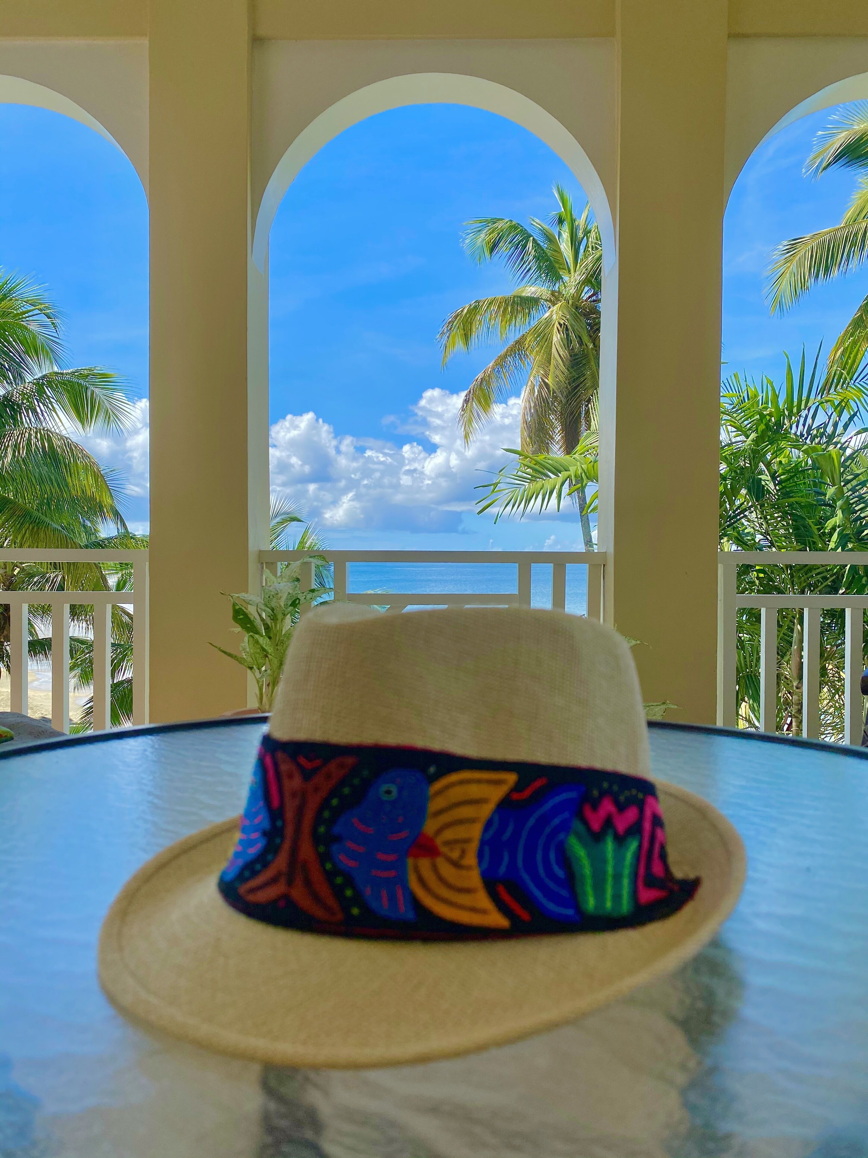 A hat on a table with a view of palm trees and a clear sky.